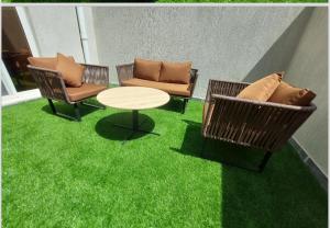 un patio con césped verde, sillas y una mesa en Elite House en Taif