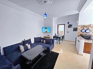 een woonkamer met een blauwe bank en een keuken bij Residence Chay - Appartement de luxe in Ouarzazate