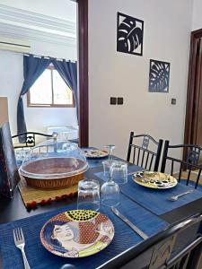 einen Tisch mit Tellern und Gläsern auf einem blauen Tischtuch in der Unterkunft Residence Chay - Appartement de luxe in Ouarzazate