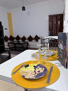 uma mesa com duas placas amarelas e copos sobre ela em Residence Chay - Luxury Appart em Uarzazate