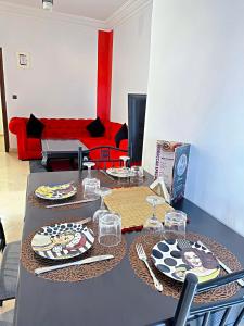 une table avec des assiettes, des verres et un canapé rouge dans l'établissement Residence Chay - Luxury Appart, à Ouarzazate
