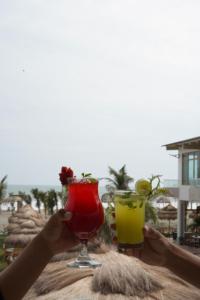 a person holding two cocktails on top of a table at Hotel Presidente Beach Playas in Playas