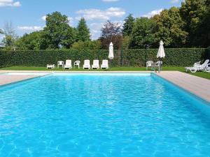 una piscina con sillas y sombrillas en un patio en Apartment Château Castelnau on a golf course in Durbuy, en Barvaux