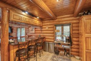 a log cabin kitchen with a bar and stools at Bear Butte Gulch Lodge in Deadwood