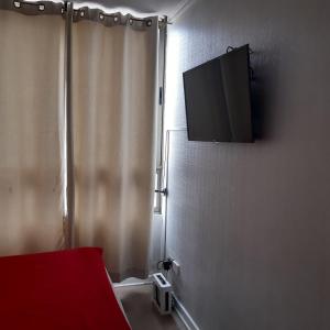 Habitación con TV en la pared con cortina en Departamento Souza, en Santiago