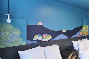 فندق كابتشينو في سول: غرفة نوم مع الوسائد البيضاء والجدار الأزرق