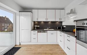 a kitchen with white cabinets and a large window at Küstenkind in Wilhelmshaven