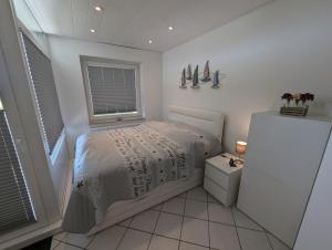 a white bedroom with a bed and a window at FeWo Heimathafen - Horumersiel in Wangerland