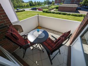 a patio with a table and chairs on a balcony at FeWo Heimathafen - Horumersiel in Wangerland