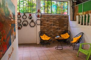 a room with two chairs and a brick wall at Hostal Raíces de mi Pueblo in Suchitoto