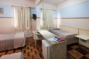 um quarto de hotel com duas camas e uma mesa e uma secretária em Oscar Hotel em Florianópolis