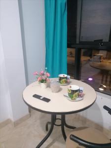 Una mesa blanca con dos tazas y flores. en Departamento-Bolognesi B1, en Chiclayo