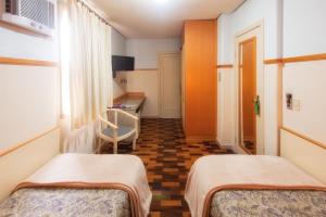 a hospital room with two beds and a desk at Oscar Hotel in Florianópolis