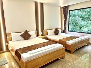 a bedroom with two beds and a large window at Cat Ba Rose Nhung Hotel in Cat Ba