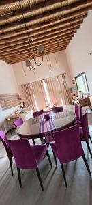 a dining room with a table and purple chairs at Casa Paraíso Huacalera rural Tilcara in Huacalera