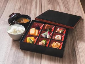 una caja de sushi y un tazón de arroz. en Hotel Rilassare Tokyo en Tokio
