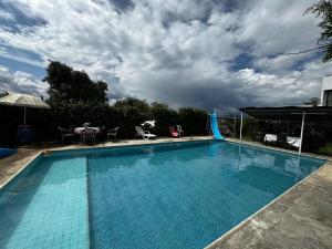 une grande piscine bleue sous un ciel nuageux dans l'établissement Casa Elalu, à Quito