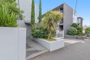 un edificio con palmeras y plantas delante de él en Contemporary 1-Bed Apartment Moments from MCG en Melbourne