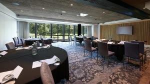 uma sala de conferências com mesas e cadeiras e um ecrã em voco Leicester, an IHG Hotel em Leicester