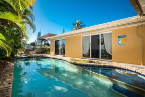 a swimming pool in front of a house at Waterfront Retreat with Private Dock-Isle of Capri in Gold Coast