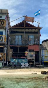 Mi Cabañita Guest House في بلايا بلانكا: منزل على الشاطئ مع كراسي وعلم