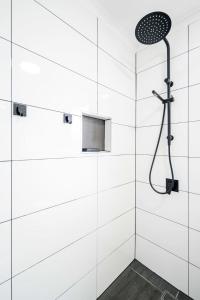 a white bathroom with a shower with a shower head at Hope Cottage - Tamborine Mountain in Mount Tamborine