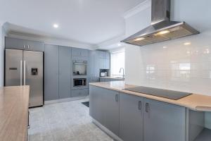 a kitchen with white cabinets and a stainless steel refrigerator at Family Escape - Serene Oasis with Pool and AC in Brisbane