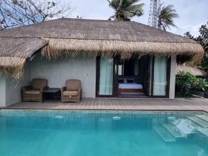 une maison au toit de chaume à côté d'une piscine dans l'établissement Mango Yard Boracay, à Boracay