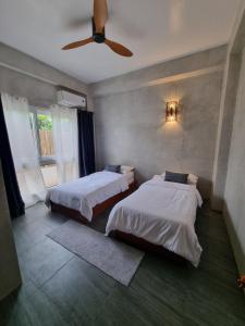 une chambre avec deux lits et un ventilateur de plafond dans l'établissement Mango Yard Boracay, à Boracay