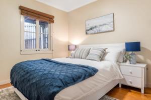 a bedroom with a white bed with a blue blanket at Elegant 4-Bedroom Residence with Entertaining Area in Brisbane