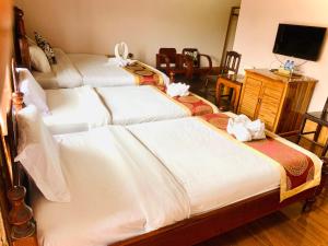 um quarto de hotel com três camas com lençóis brancos em Happy Riverview Hotel em Vang Vieng