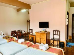 um quarto de hotel com três camas e uma televisão de ecrã plano em Happy Riverview Hotel em Vang Vieng