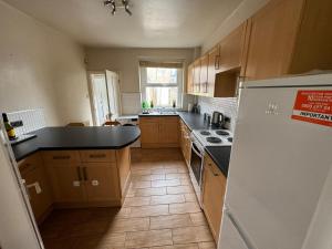 a kitchen with wooden cabinets and a black counter top at Cumberland House-2 Bed House in Workington