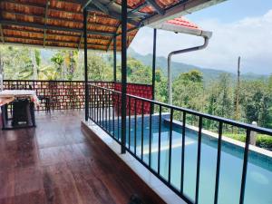 a balcony with a pool and mountains in the background at Mayflower Holiday Villa in Meppādi