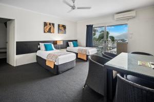 a hotel room with two beds and a balcony at Colonial Palms Motor Inn in Airlie Beach