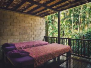 porche con 2 camas y balcón con árboles en Hanging Gardens of Bali en Payangan