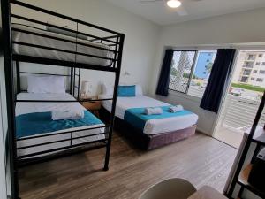 a bedroom with two bunk beds and a window at Bargara Beach Hotel in Bargara