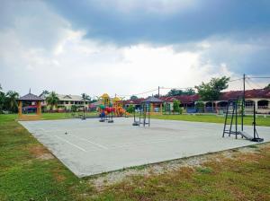 a park with a tennis court with a playground at Homestay Melewar in Parit Raja