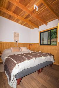 Cama grande en habitación con techo de madera en Wincarayen Lodge & Cabañas, en Panguipulli