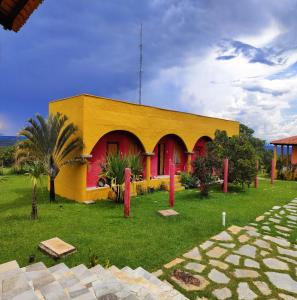 um edifício amarelo e vermelho com palmeiras em frente em Villa dos Pireneus em Pirenópolis
