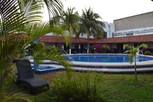 una piscina con una silla y palmeras en un patio en Hotel Plaza Almendros, en Isla Mujeres
