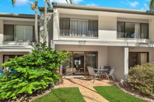 a house with a patio with a table and chairs at 10 Noosa Sound in Noosa Heads