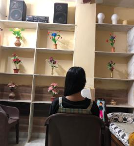 una mujer sentada en una silla mirando flores en los estantes en The Green House Impact en Jodhpur