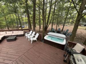 une terrasse avec un bain à remous, des chaises et des arbres dans l'établissement Luxury Family Escape HotTub Sauna Billiard Pool home, à East Stroudsburg