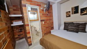 Habitación pequeña con cama y pared de ladrillo en Gran Caribe Hotel en Medellín