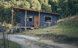 una casa azul en una colina al lado de un camino de tierra en Wincarayen Lodge & Cabañas en Panguipulli