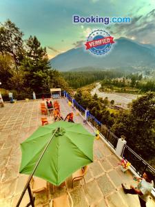 a green umbrella on a patio with a view of a river at The Four Season Hotel & Resort, Manali in Manāli