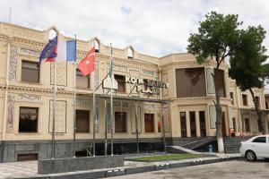 un bâtiment avec trois drapeaux devant lui dans l'établissement Ko'k Saroy Plaza Hotel, à Samarcande