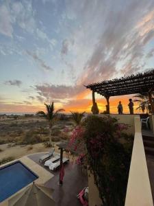2 persone in piedi su un balcone che osservano il tramonto di Todas Las Familias, Baja Dream House a Todos los Santos