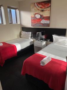 a hotel room with two beds with red sheets at Apartments on Chapman in Melbourne
